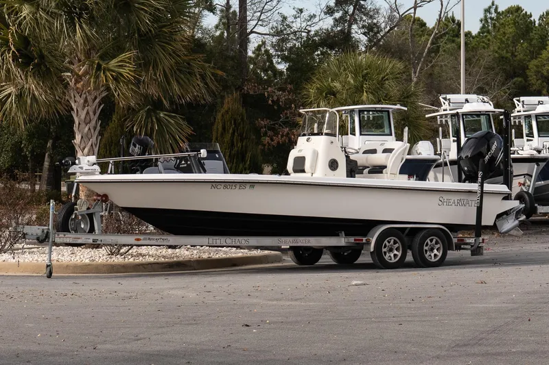 Slide: The Image of 2021 ShearWater 25LTD boat on trailer, parked near palm trees. - 2