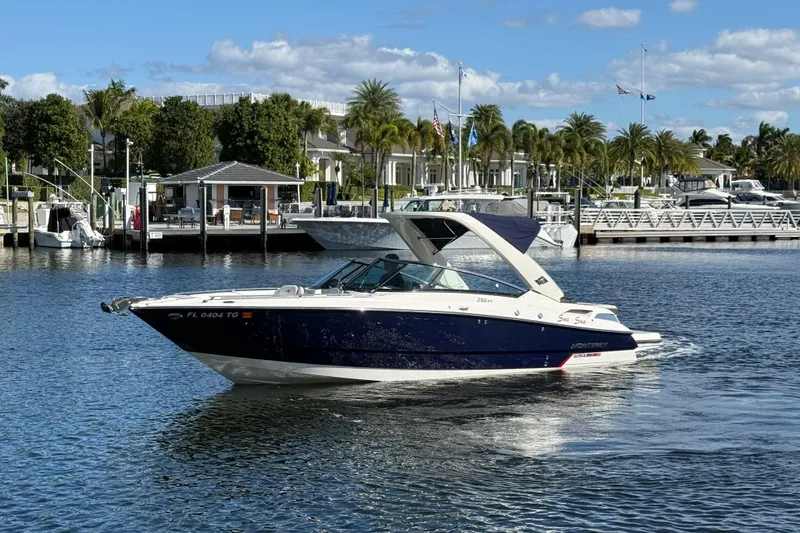 Slide: The Image of 2017 Monterey 298SS Super Sport boat cruising in a marina with palm trees and docks. - 14