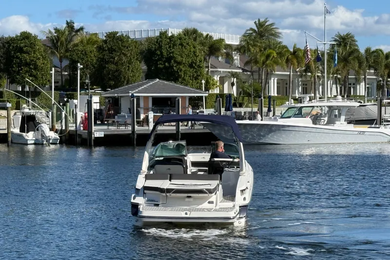 Slide: The Image of 2017 Monterey 298SS Super Sport boat cruising near a marina with palm trees and docks. - 16