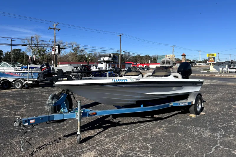 Slide: The Image of 2003 Champion 187 CX boat on trailer in parking lot, clear blue sky background. - 2