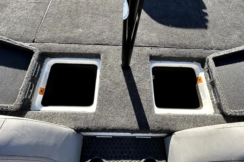 Slide: The Image of 2003 Champion 187 CX boat storage compartments with open hatches on carpeted deck. - 24