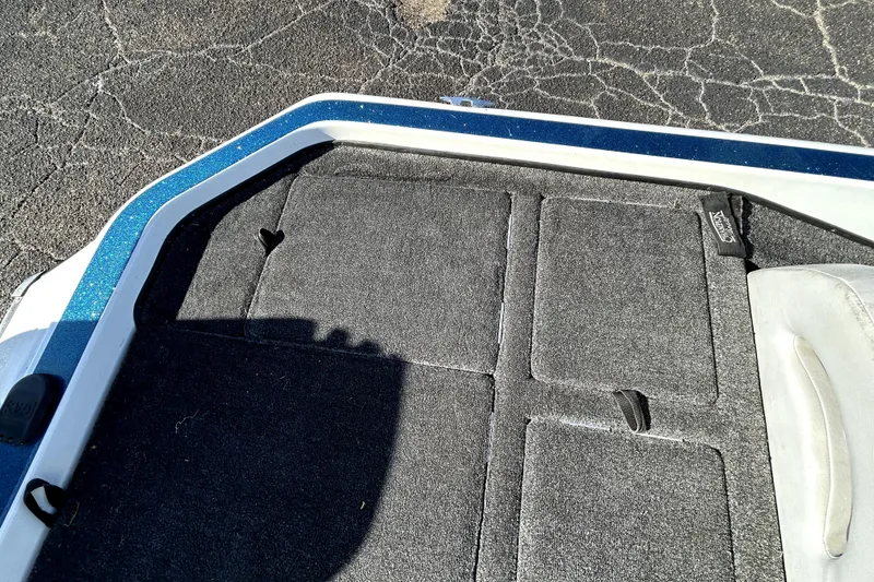 Slide: The Image of 2003 Champion 187 CX boat deck with gray carpet and storage compartments. - 25