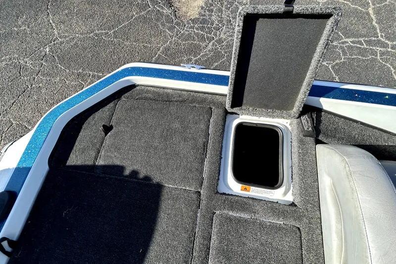 Slide: The Image of 2003 Champion 187 CX boat storage compartment with open hatch on carpeted deck. - 26