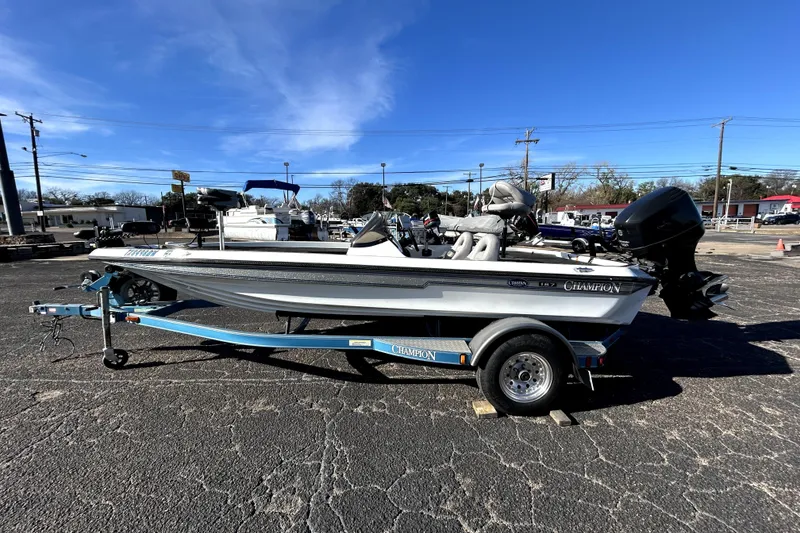 Slide: The Image of 2003 Champion 187 CX boat on trailer in parking lot under clear blue sky. - 3