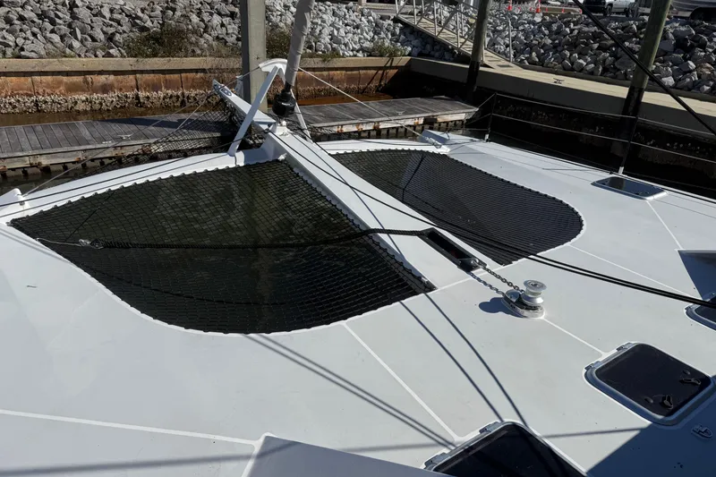 Slide: The Image of 2023 Schionning 1850 S catamaran deck with netting, docked at a marina. - 6