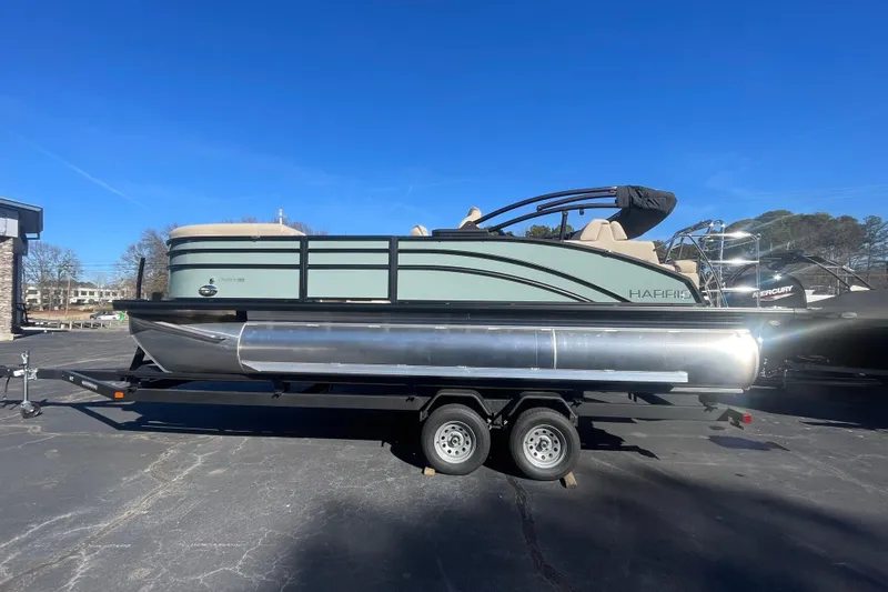The Image of 2026 Harris Cruiser 210 pontoon boat on trailer under clear blue sky. - 1