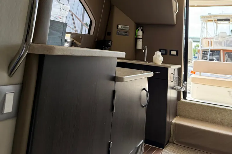 Slide: The Image of Interior of 2013 Carver C34 yacht, featuring a compact kitchen area with modern cabinetry. - 13