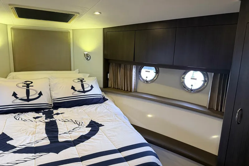 Slide: The Image of Luxurious 2013 Carver C34 yacht bedroom with nautical-themed bedding and porthole windows. - 16
