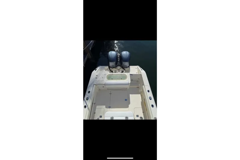 Slide: The Image of 2009 Pursuit S 310 Sport boat interior with steering wheel and controls, docked on calm water. - 17