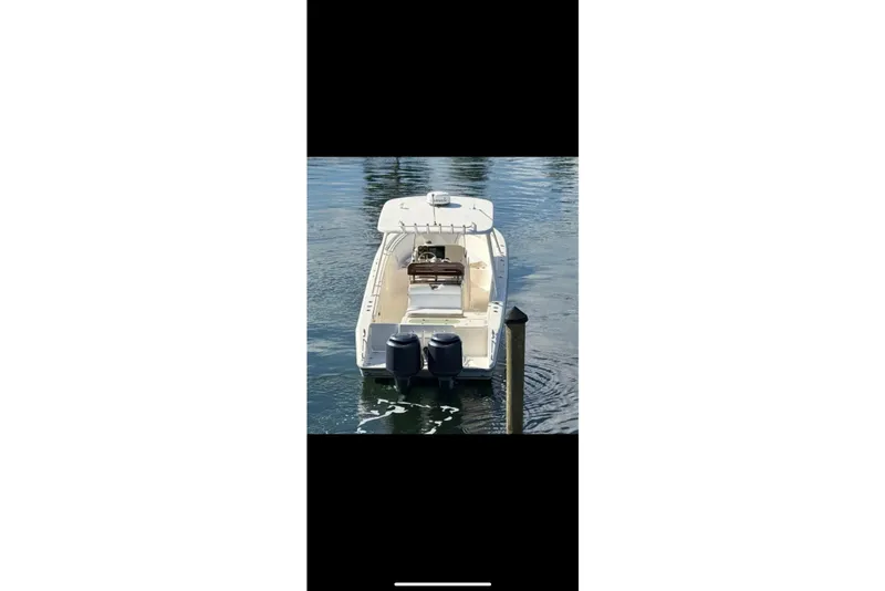 Slide: The Image of 2009 Pursuit S 310 Sport boat on calm water, surrounded by palm trees and waterfront homes. - 6