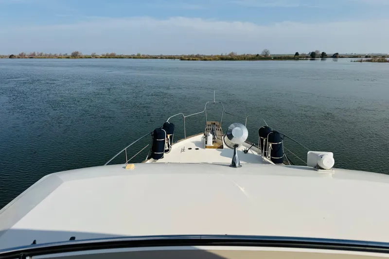 Slide: The Image of 1987 Bayliner 4550 Motoryacht cruising on calm waters under a clear sky. - 12