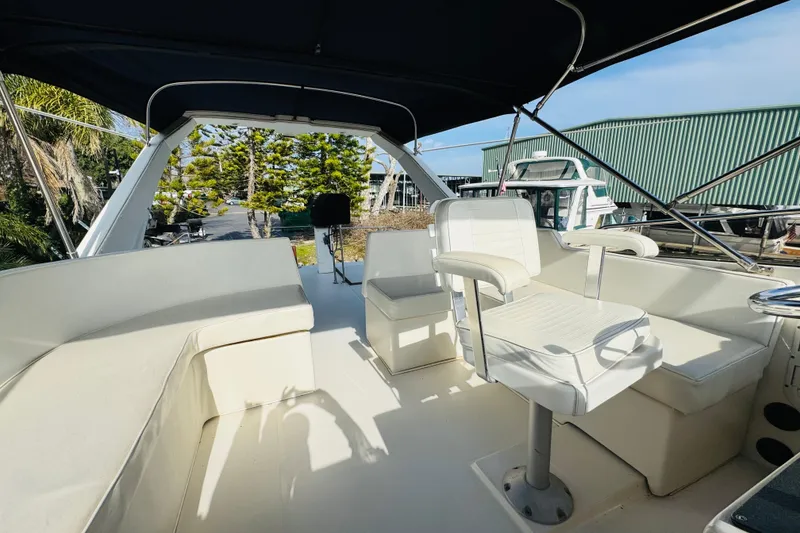 Slide: The Image of 1987 Bayliner 4550 Motoryacht flybridge with white seating and canopy, docked outdoors. - 27