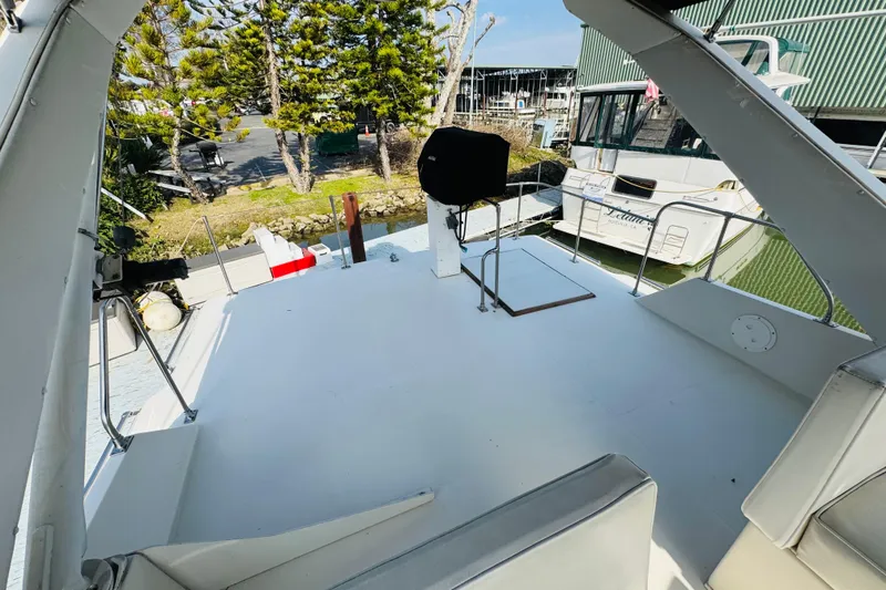 Slide: The Image of 1987 Bayliner 4550 Motoryacht deck with seating, docked near trees and other boats. - 28