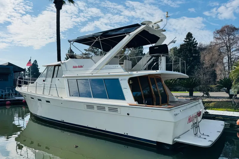 Slide: The Image of 1987 Bayliner 4550 Motoryacht docked, featuring sleek design and spacious deck under a blue sky. - 3