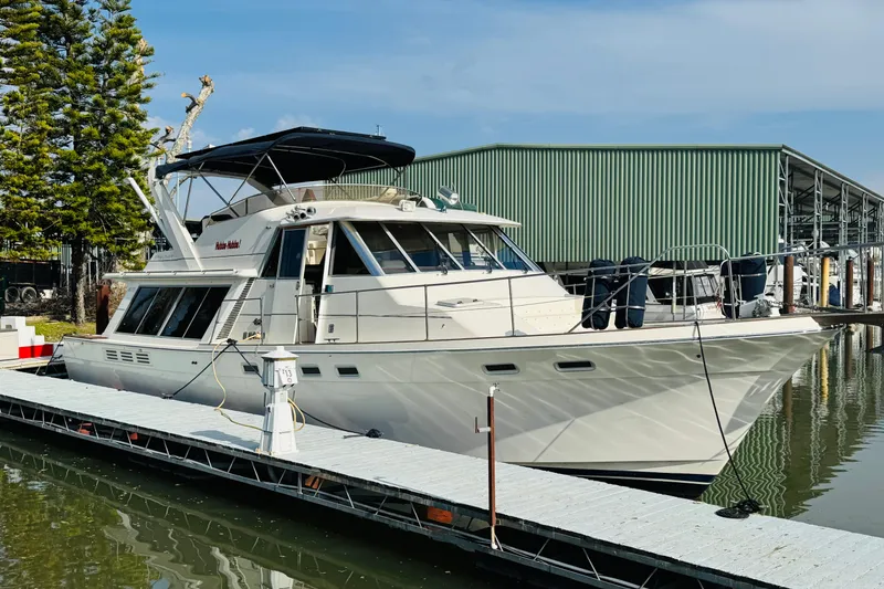 Slide: The Image of 1987 Bayliner 4550 Motoryacht docked at marina, surrounded by calm water and trees. - 4