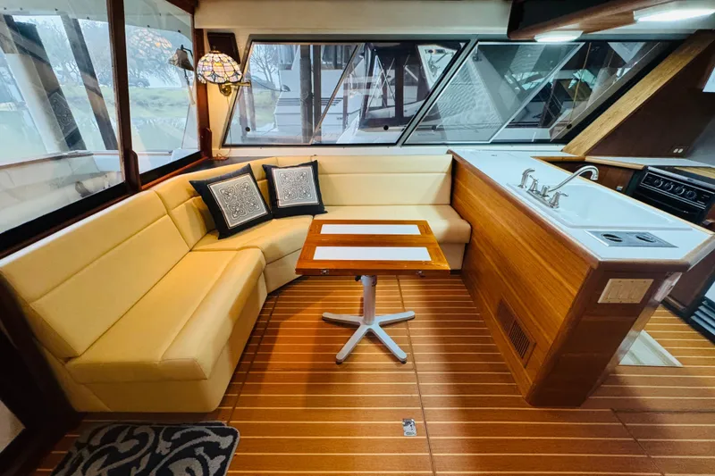 Slide: The Image of 1987 Bayliner 4550 Motoryacht interior with cozy seating, wooden table, and kitchenette. - 44