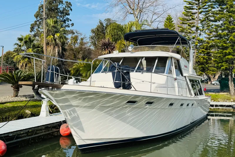 Slide: The Image of 1987 Bayliner 4550 Motoryacht docked, surrounded by lush greenery and calm waters. - 5