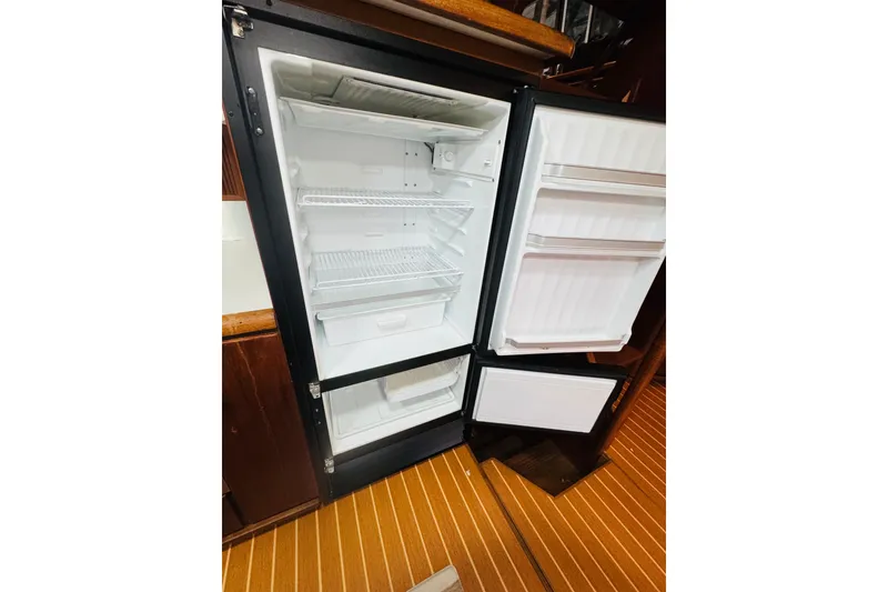 Slide: The Image of Open refrigerator inside 1987 Bayliner 4550 Motoryacht, showcasing spacious interior and wooden flooring. - 51