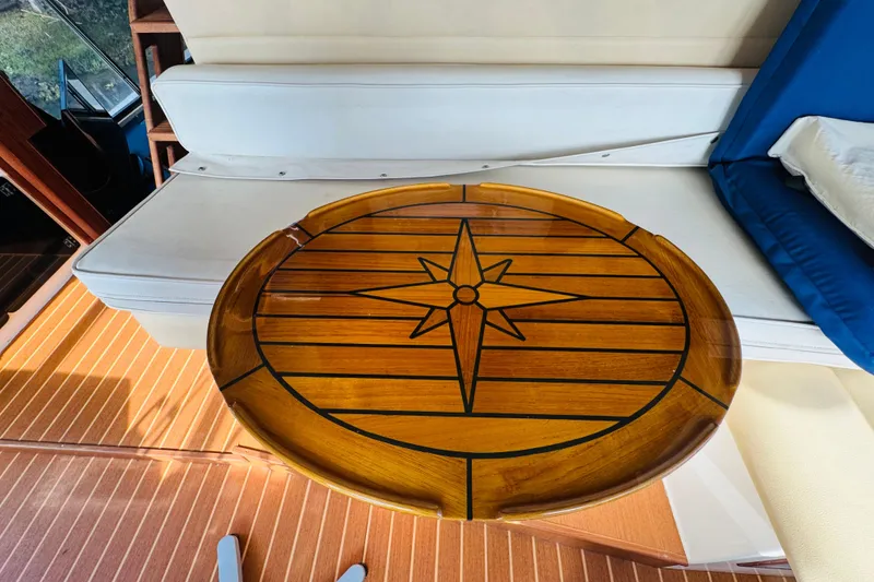 Slide: The Image of Interior of 1987 Bayliner 4550 Motoryacht with wooden compass rose table and white seating. - 61