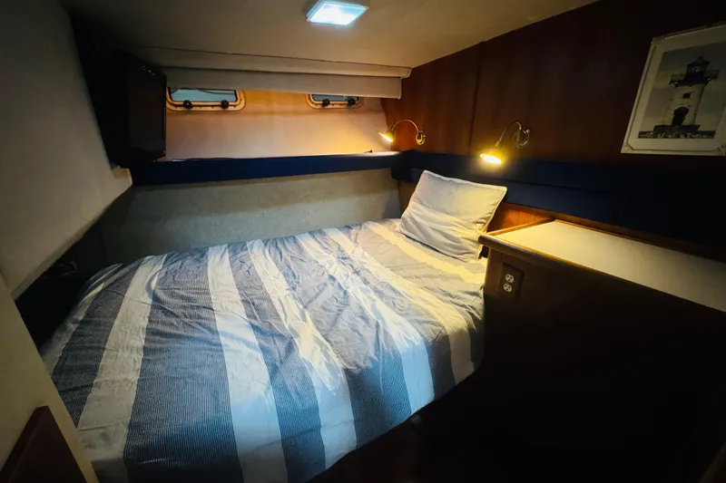 Slide: The Image of Cozy bedroom in 1987 Bayliner 4550 Motoryacht with striped bedding and warm lighting. - 70