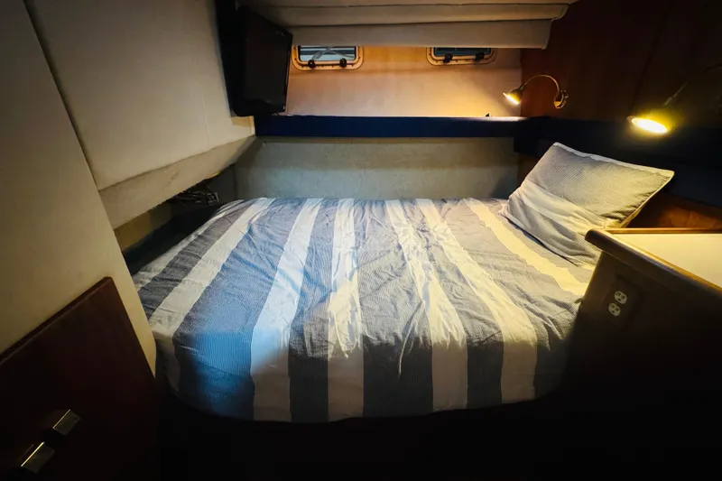 Slide: The Image of Cozy bedroom in 1987 Bayliner 4550 Motoryacht with striped bedding and warm lighting. - 71