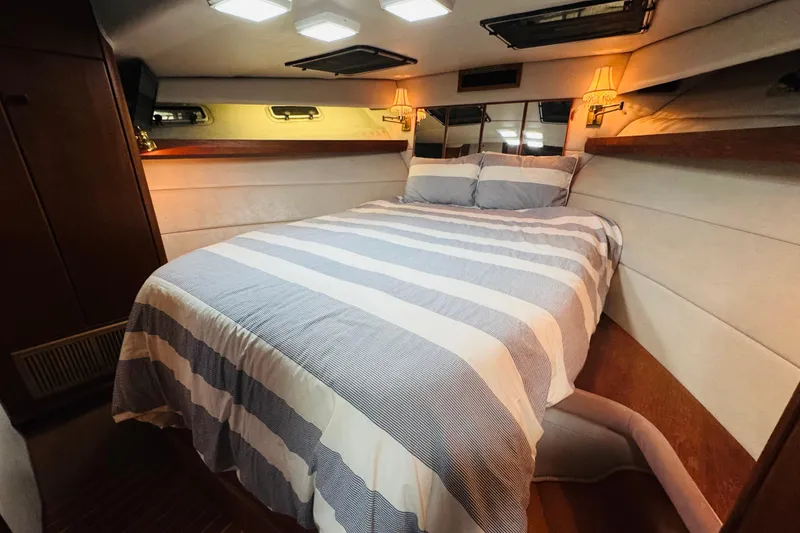 Slide: The Image of 1987 Bayliner 4550 Motoryacht bedroom with striped bedding and cozy lighting. - 79