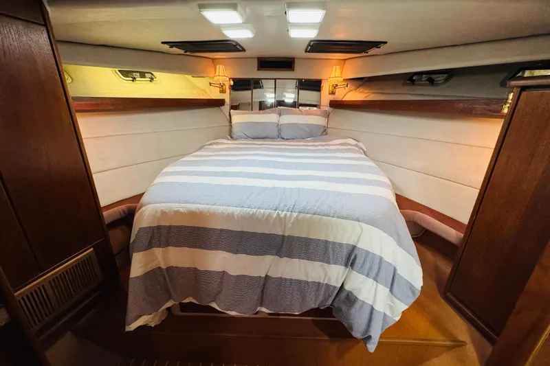 Slide: The Image of Cozy bedroom in 1987 Bayliner 4550 Motoryacht with striped bedding and warm lighting. - 80