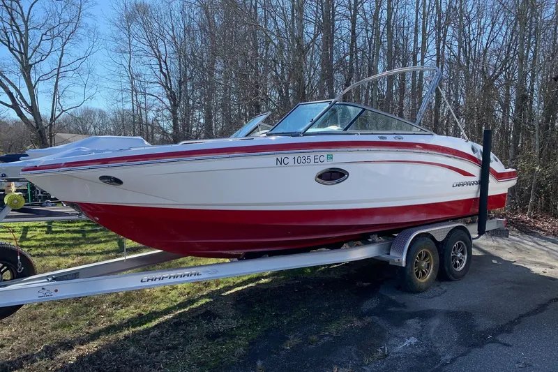 The Image of 2015 Chaparral 246 SSi boat on trailer, red and white, parked near trees. - 0