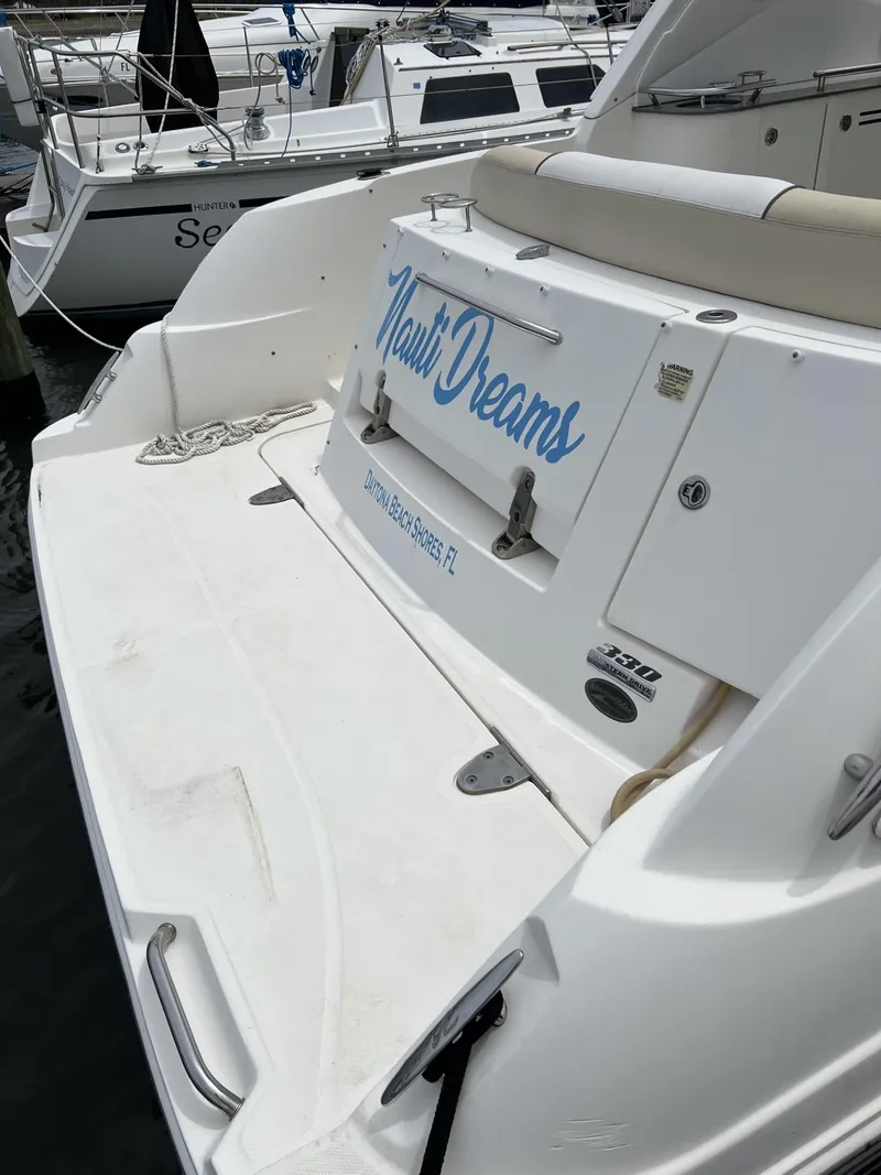 Slide: The Image of 2012 Sea Ray Sundancer boat docked, featuring "Nauti Dreams" name on the stern. - 16