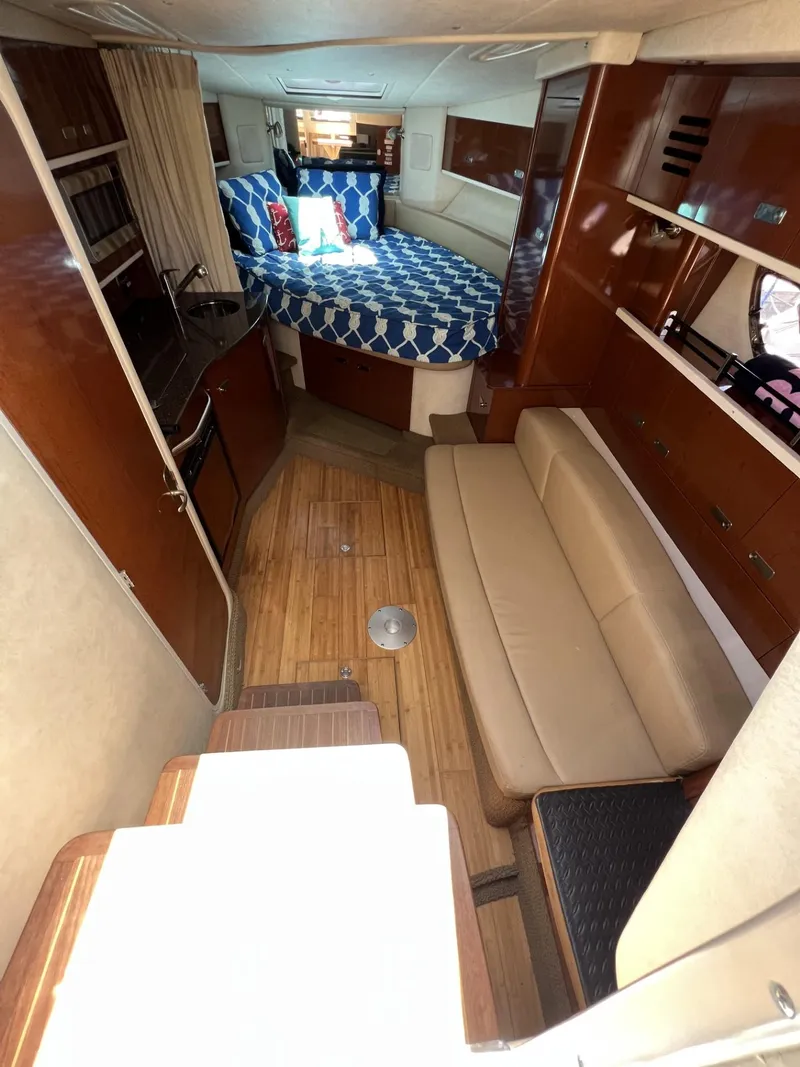 Slide: The Image of 2012 Sea Ray Sundancer interior with cozy seating, bed, and wooden flooring. - 29