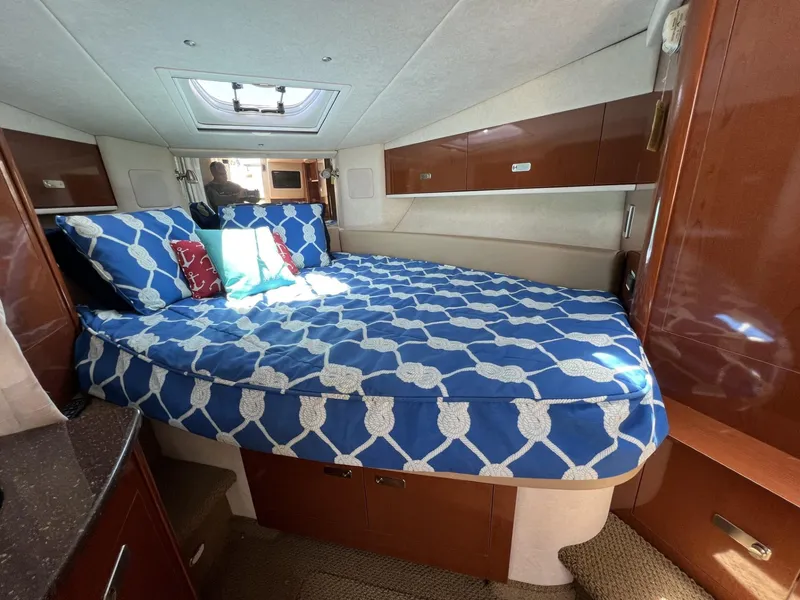 Slide: The Image of 2012 Sea Ray Sundancer cabin with blue patterned bedding and wooden cabinetry. - 35