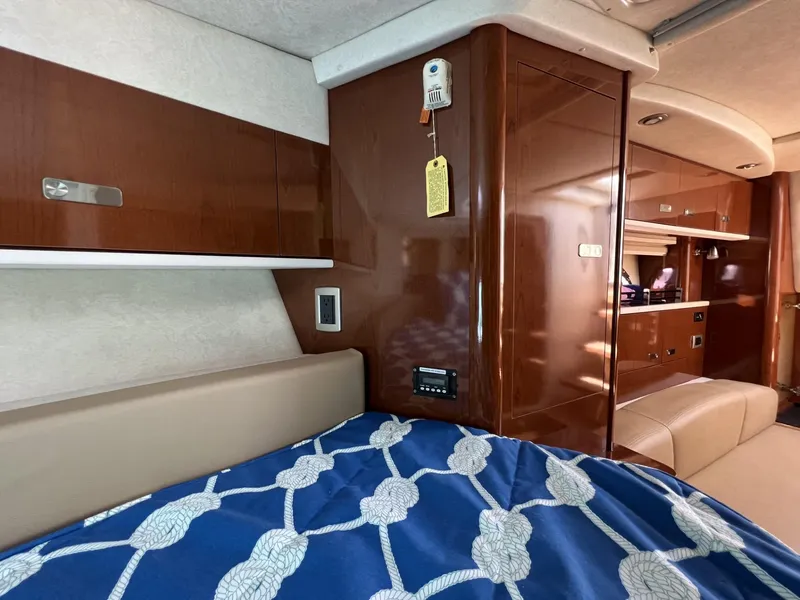 Slide: The Image of Interior of 2012 Sea Ray Sundancer with wood paneling and nautical-themed bedding. - 38