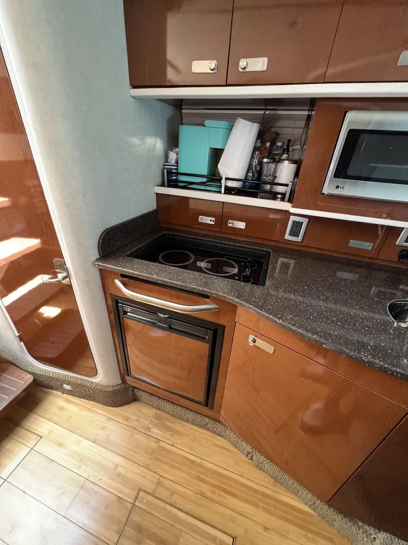 Slide: The Image of 2012 Sea Ray Sundancer kitchen with stove, microwave, and wooden cabinetry. - 42