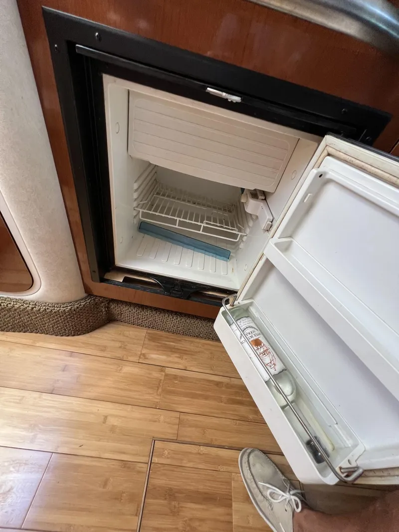Slide: The Image of Open refrigerator inside 2012 Sea Ray Sundancer boat, showing interior shelves and door storage. - 43