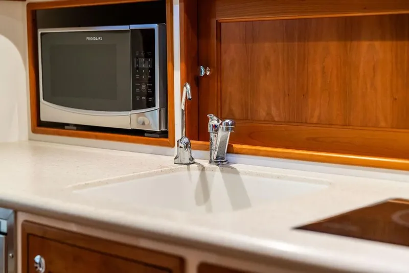 Slide: The Image of Luxury yacht MJM 35z 2018 galley with microwave, sink, and wooden cabinetry. - 26