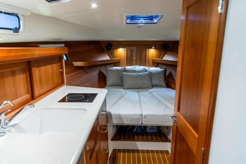 Slide: The Image of 2018 MJM 35z yacht interior with cozy bed, wooden cabinetry, and compact kitchen area. - 27