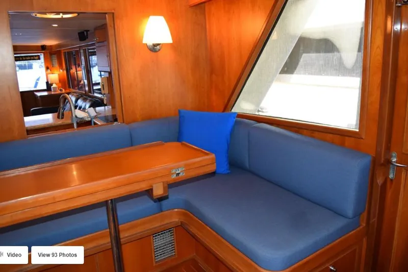 Slide: The Image of 2002 Grand Alaskan Cockpit Motor Yacht interior with blue seating and wooden table. - 12