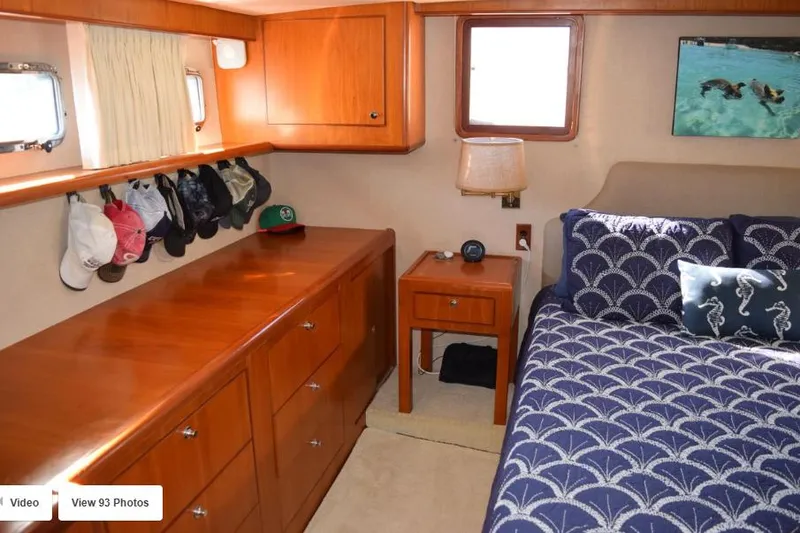 Slide: The Image of 2002 Grand Alaskan Cockpit Motor Yacht bedroom with wooden cabinets and nautical-themed bedding. - 34