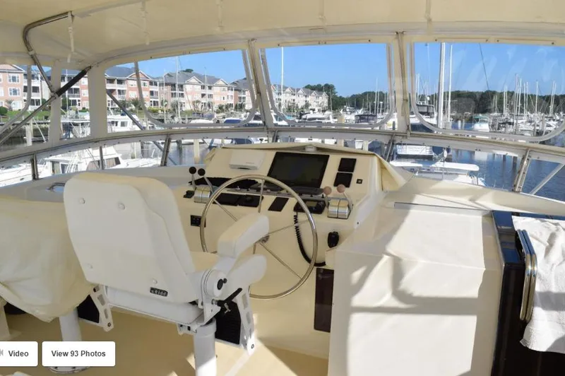 Slide: The Image of 2002 Grand Alaskan Cockpit Motor Yacht helm with marina view, featuring navigation controls and seating. - 7
