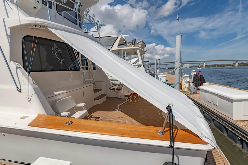 Slide: The Image of 2003 Ocean Yachts 62 Super Sport EB docked, featuring a shaded deck and clear blue sky. - 7
