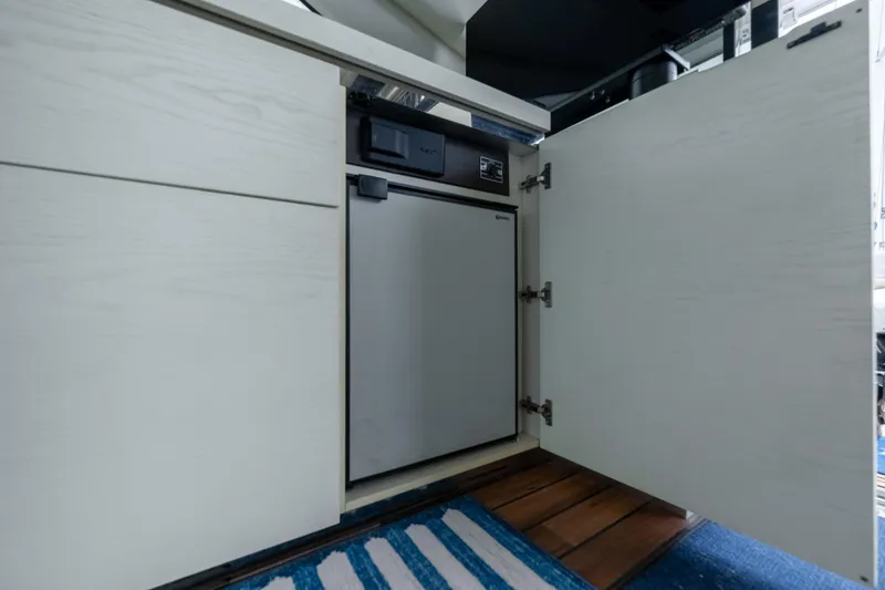 Slide: The Image of 2015 Azimut 55S yacht interior with open cabinet revealing compact refrigerator. - 51