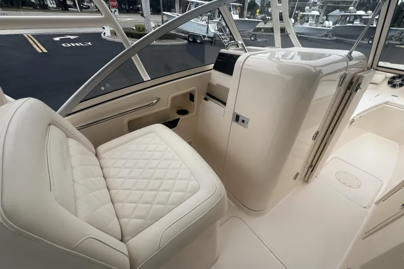 Slide: The Image of 2020 Grady-White Freedom 235 boat interior with seating and helm, parked near road. - 7