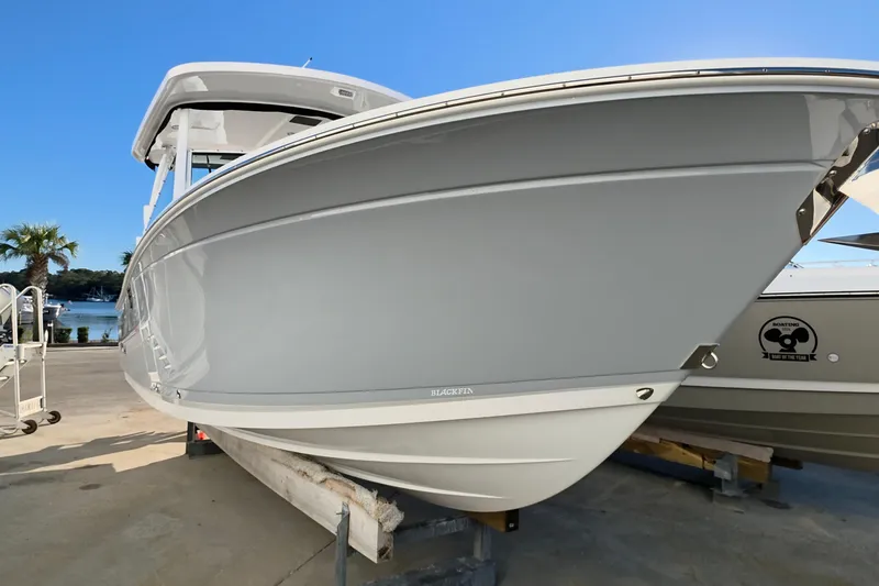 The Image of 2021 Blackfin 272 DC boat on display at a marina under clear blue skies. - 0