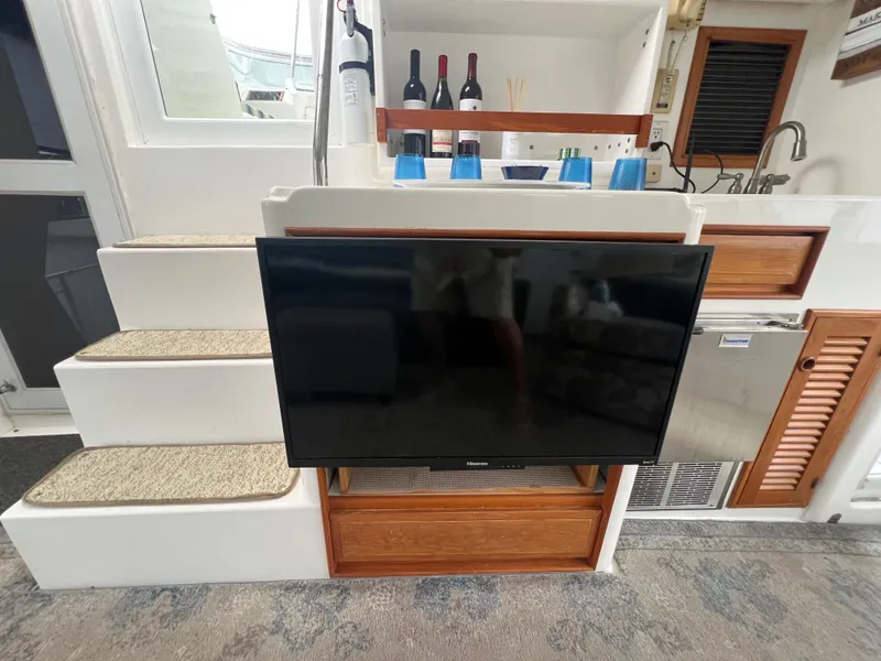 Slide: The Image of 1998 Hyatt 51 Aft Cabin Motor Yacht interior with TV, stairs, and kitchenette. - 31