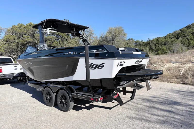 Slide: The Image of 2021 Tigé 23ZX boat on trailer, rear view, sunny day, residential background. - 11