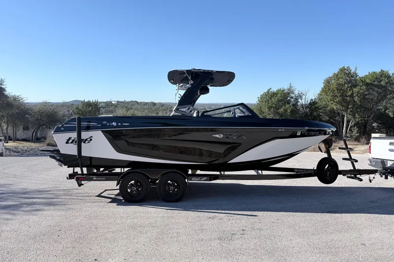 Slide: The Image of 2021 Tigé 23ZX boat docked in a covered marina, showcasing sleek design and modern features. - 13