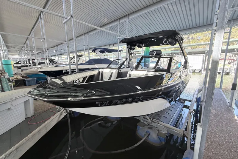 Slide: The Image of 2021 Tigé 23ZX boat docked in a marina, featuring sleek black and white design. - 14