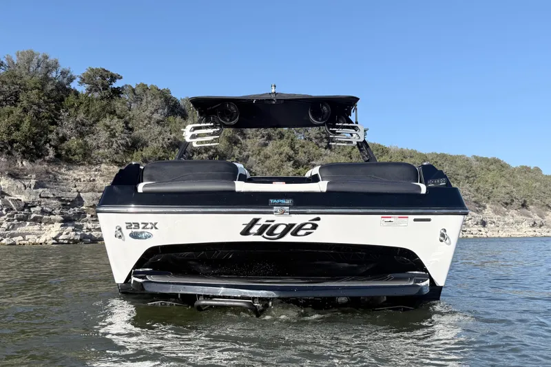 Slide: The Image of 2021 Tigé 23ZX boat on a lake with rocky shoreline and clear blue sky. - 5