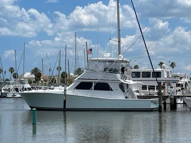 The Image of 1991 Viking Convertible yacht docked in a marina under a partly cloudy sky. - 0