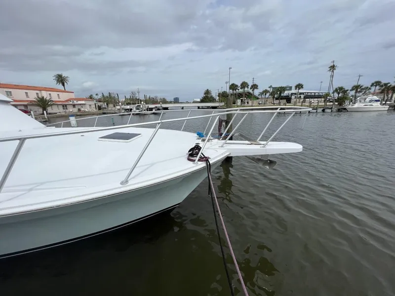 Slide: The Image of 1991 Viking Convertible boat docked in a marina with palm trees and cloudy sky. - 13